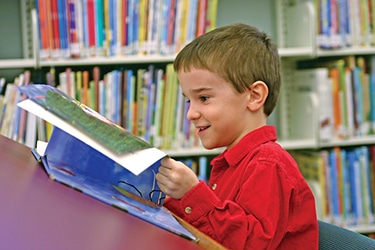 boy reading a book at the library