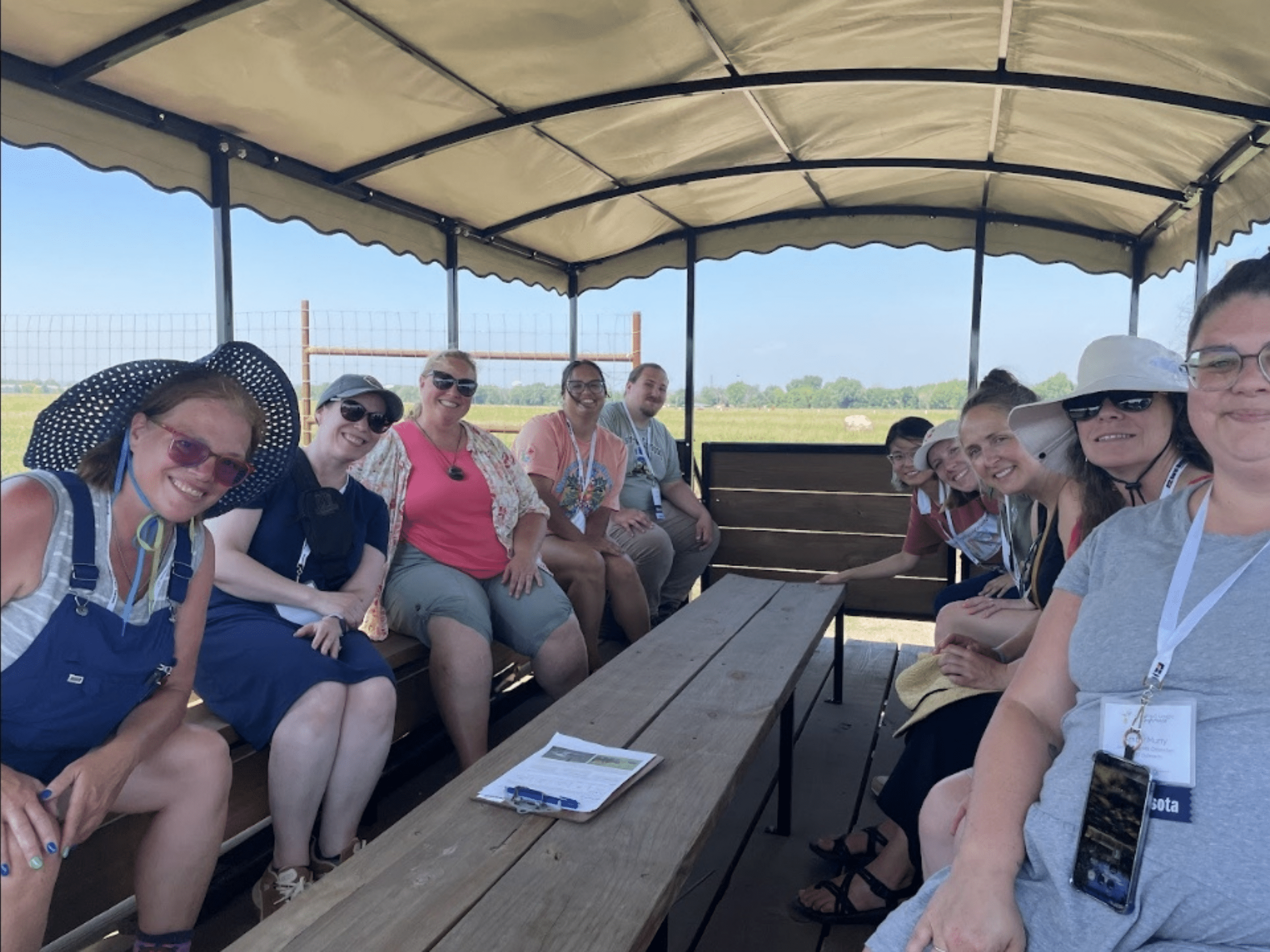 A group of people sitting on benches inside a covered trailer posing for a photo