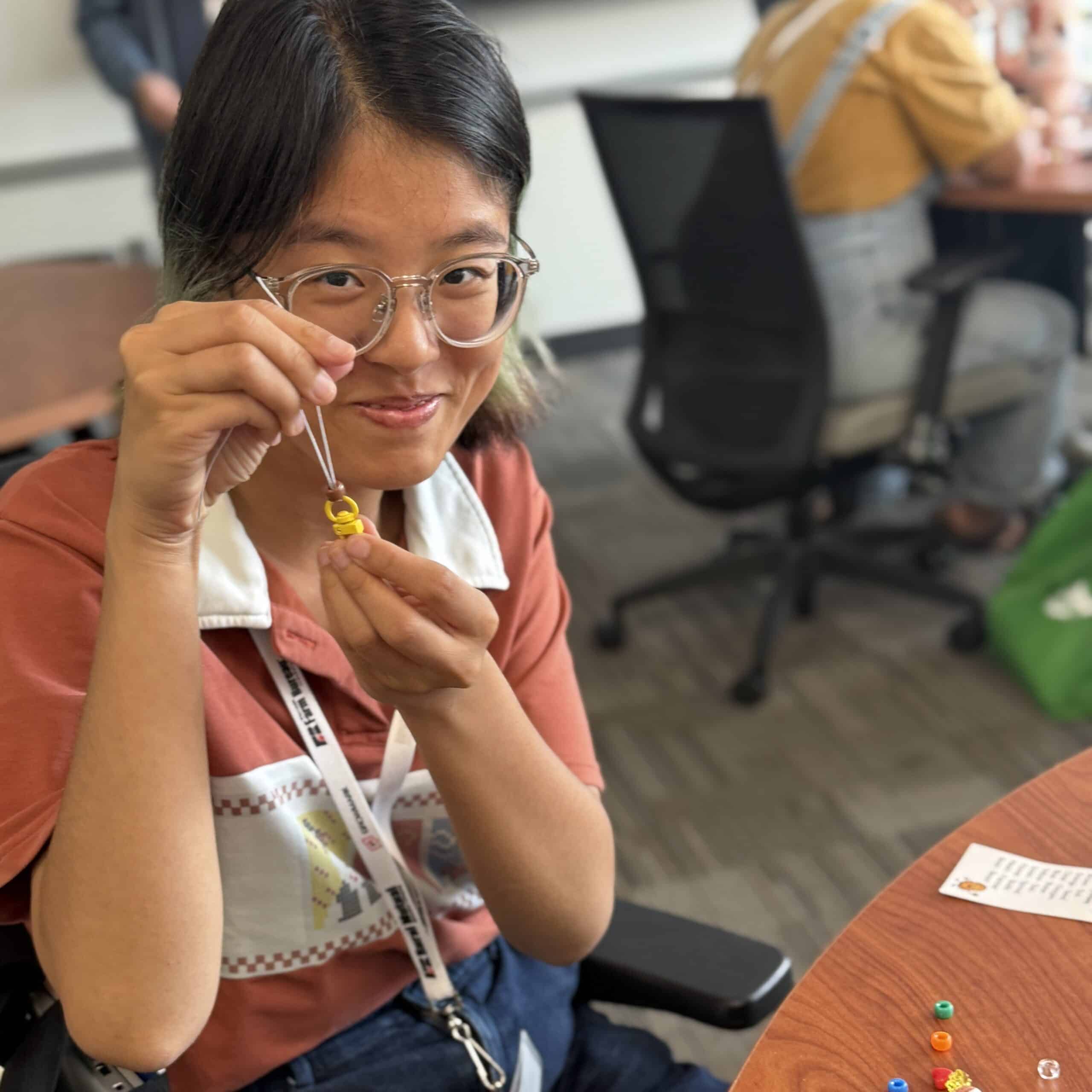 Person smiling and holding up a keychain made from dried beans