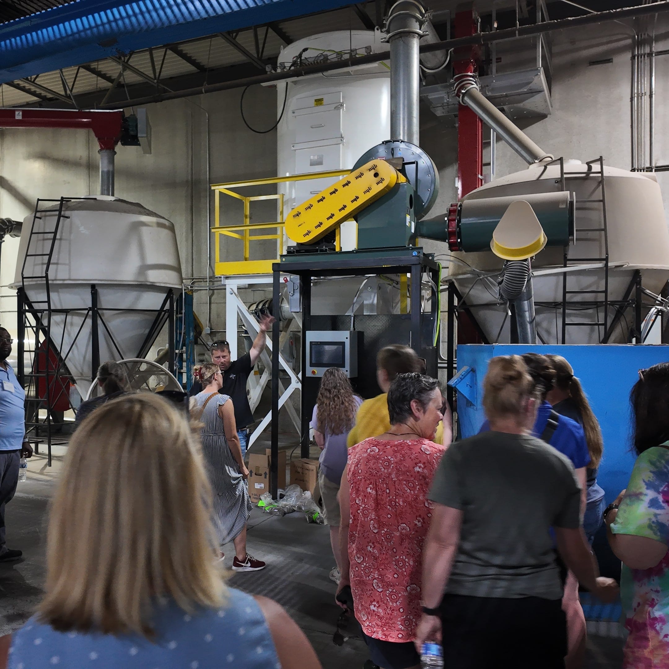 A group of people looking around at large machines inside a warehouse